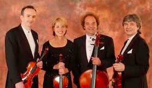 Photo of the Takacs Quartet in formal attire with their instruments.